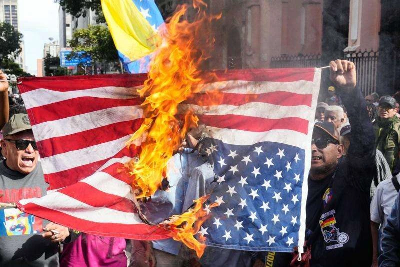 Anti-imperialistas quemando la bandera estadounidense en protesta contra la intervención militar para la captura de Maduro en 2026.
